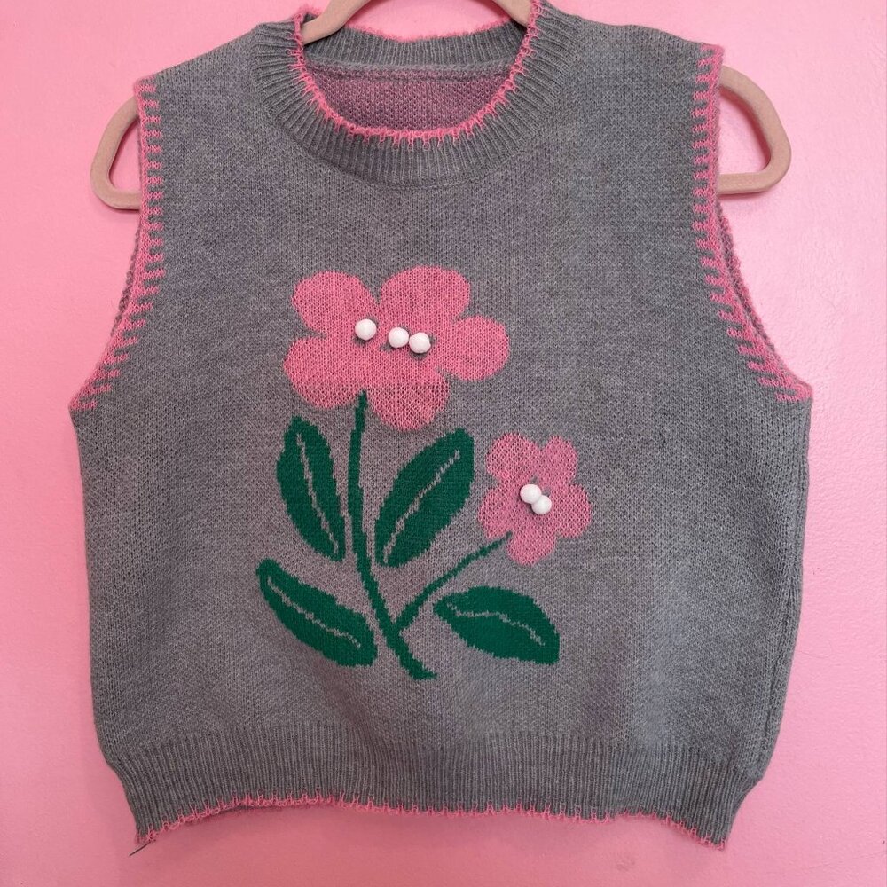 Grey sweater vest with pom poms.